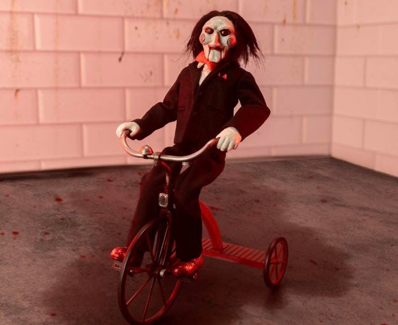NECA ULTIMATE SAW BILLY THE PUPPET RIDING TRICYCLE WITH SOUND - 33 CM | | Figuras De
